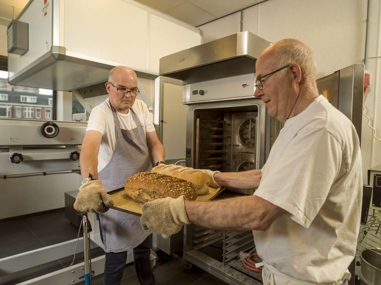 Clienten halen brood uit oven